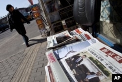 一名北京市民2月16日走过街头报摊,报纸头版刊登中国副主席习近平与奥巴马总统在白宫会晤的照片