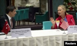 FILE - Then-Foreign Affairs Minister Ahmet Davutoglu of Turkey listens to U.S. Secretary of State Hillary Clinton as they attend a "Friends of Syria" meeting in Istanbul, June 6, 2012.