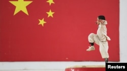 少林寺的武术学生在河南省郑州市一面中国国旗前表演武术。(2018年6月6日)