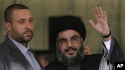 资料照片:黎巴嫩真主党领导人纳斯鲁拉在保镖卡纳什(左)的保护下在贝鲁特向支持者招手。(2006年9月22日)