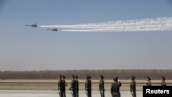 中国士兵们站立在辽宁沈阳一个机场上,空军两架歼-11战机飞越上空。 (2019年4月3日)