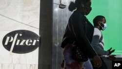 Pejalan kaki berjalan melewati kantor pusat Pfizer di New York, 9 November 2020. (Foto: AP)