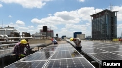 在中国浙江省义乌市国际商贸城的屋顶,工人安装太阳能电池板(2017年7月17日)。