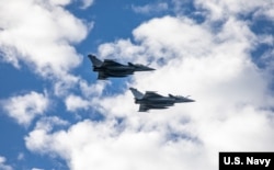 资料照片:2022年11月16日,两架法国“阵风”战斗机飞过美国海军“罗斯福号”导弹驱逐舰。(美国海军照片)