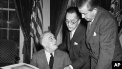 1941年10月10日,中国驻美大使胡适博士(中)向美国总统罗斯福(左)解说含有中国一万师生签名的书册