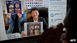 一名男子正在看台湾外交部脸书网页,网页上的台湾卫生部长陈世忠举着标语牌宣传预防新冠病毒。(2020年2月14日)