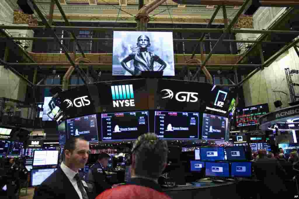 无畏女孩像的影像投射在纽约证券交易所里,交易员们在工作(2018年12月10日) 。