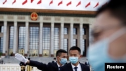 预防病毒传播和减少感染新冠病例,戴口罩可能比保持社交距离或者禁足在家都更为重要。中国保安在正在举行中国人大会议的北京人大会堂外站岗。(路透社2020年5月25日资料照)