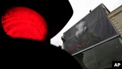 英国工人在伦敦前卫艺术展览馆里森艺术馆外悬挂两层楼高的艾未未黑白照片,为艾未未的艺术展做准备。 (资料照片 2011年5月11日)