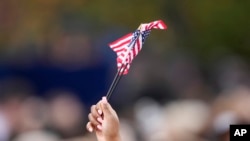 2024年11月6日,卡马拉·哈里斯的支持者在华盛顿霍华德大学校园里挥舞着美国国旗,等待哈里斯抵达并发表总统选举败选演说。