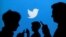 2013年9月27日，人们看手机的剪影，背景是推特的标徽小鸟。 