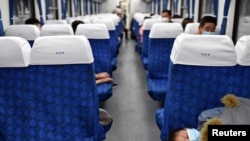 资料照:湖北武昌火车站里戴着口罩的旅客在火车车厢里休息。(2020年4月8日)