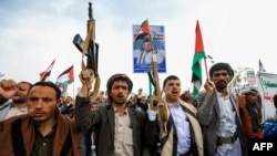抗议人士在也门胡塞武装控制区举着也门和巴勒斯坦旗帜集会,支持巴勒斯坦人。(2024年7月19日)