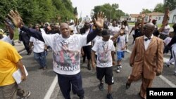 弗格森警察枪击案死者布朗的父亲(中)与抗议者一道游行纪念该事件一周年。