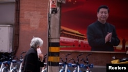 一名戴着口罩的妇女从上海街头一幅习近平的画像前走过。(2020年3月12日)