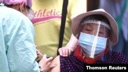 A medical worker administers a dose of the Moderna vaccine against the coronavirus disease (COVID-19) to a woman during a vaccination session at the National Taiwan Science Education Center in Taipei City, July 3, 2021.