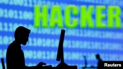 在“黑客”字样前,一名男子正在操作电脑。(2021年7月5日)