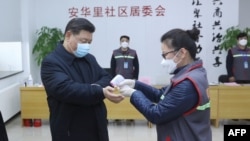 中国国家主席习近平戴着口罩视察北京安华里小区时一名防疫人员检测他的体温。(2020年2月10日)