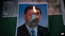 2020年6月4日,星期四,在香港铜锣湾维多利亚公园为1989年天安门广场大屠杀遇难者举行的守夜仪式上,中国国家主席习近平的照片上燃烧着一支蜡烛。