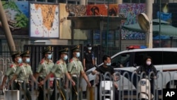 资料照片： 在美国驻北京大使馆外守卫的保安看一队武警走过。（2022年8月3日）