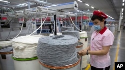 资料照片:在中国政府组织的外国记者参观期间,工人在位于新疆维吾尔自治区阿克苏的华孚时尚工厂内作业。(2021年4月20日)