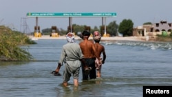 巴基斯坦南部信德省塞赫万地区的民众在被洪水淹没的高速公路上行走。(2022年9月16日)