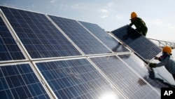 资料照片:工人们在中国新疆的一个光伏电站安装太阳能电池板。