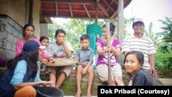 Mahniwati (kiri bertopi) bersama sebuah keluarga petani saat menumbuk kulit cangkang kopi menjadi green bean. (Foto: Dok Pribadi)