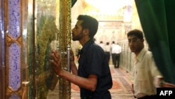 资料照片：一名伊朗男子正在亲吻灯王之墓的大门。