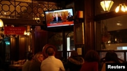 2020年10月31日在伦敦的一个酒吧里,顾客看着电视上英国首相约翰逊宣布新的疫情封锁措施。