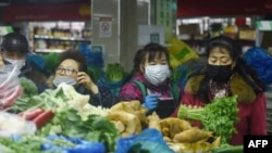 中国浙江省杭州市的一家超市里顾客戴着口罩购买蔬菜。(2020年2月9日)