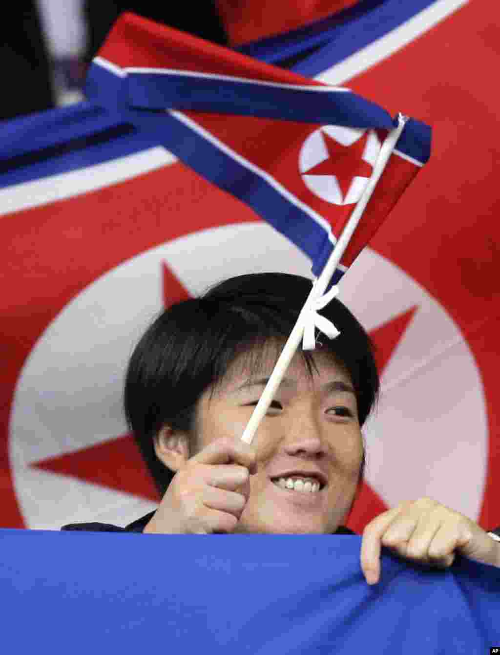 Một cổ động viên Bắc Triều Tiên vẫy cờ trước trận đấu bóng đá nữ bảng G với đội Mỹ tại sân vận động Old Trafford ở Manchester, 31 tháng 7, 2012. (AP Photo/Jon Super)