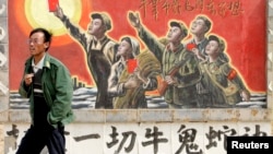 资料照:一名男子走过宁夏银川街头郊区的一处描写中国文革的宣传画。(2007年4月25日)