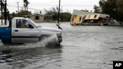 德克萨斯遭受飓风“哈维”侵袭地区积水严重,一辆卡车在积水中驶过一幢受损严重的房子(2017年8月26日)