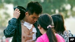 Một người đàn ông bị thương bước ra khỏi bệnh viện nơi chăm sóc các nạn nhân vụ nổ ở Thiên Tân, 13/8/2015.