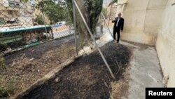 联合国近东救济工程处约旦河西岸事务主任亚当·布鲁克斯(Adam Bouloukos)向人们展示该机构总部旁被当地以色列居民纵火焚烧后的情景。(2024年5月10日)