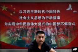 一名男子走过北京街头宣传习近平指示的各族人民大团结中国梦的广告牌。（20218年9月11日）