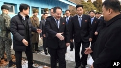 朝鲜首席代表、和平统一委员会主席李善权(中)在板门店非军事区走过边界时与迎接他的韩国官员握手(2018年1月9日)