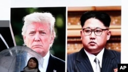 在东京,一位女士走过显示美国总统川普和朝鲜领导人金正恩的巨大屏幕。(2018年3月9日)