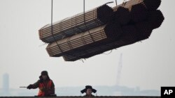 资料图片-2012年2月20日,在中国唐山曹妃甸港口,工人把钢管装船。