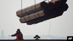 在中国唐山曹妃甸港口,工人把钢管装船。(2012年2月20日)中国钢铁产品受到欧盟制裁