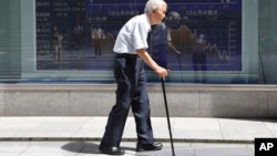 档案照: 2016年8月19日,一名年迈男子经过东京一家证券公司的股市电子行情牌。