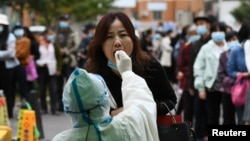 中国青岛的医护人员正在给一名妇女做核酸检测。(2020年10月13日)