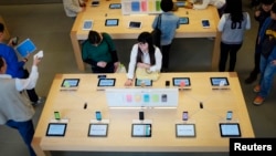 北京三里屯的一家苹果商店里,顾客在看展示出来的苹果手机及其他苹果产品。