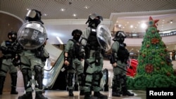 香港防暴警察在一个商场中站在一棵圣诞树旁面对示威者。(2019年12月24日)