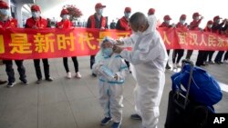 武汉解封,天河国际机场的旅客站在庆祝的标语横幅旁。(2020年4月8日)