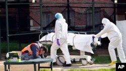 Medical personnel transport a body from a refrigerated container at Kingsbrook Jewish Medical Center, April 8, 2020, in the Brooklyn borough of New York.