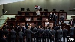 在香港的一次立法会会议上,亲民主议员(上)在一场关于禁止侮辱中国国歌的法律的辩论中被保安(下)阻挡。(2020年6月4日)