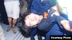 香港学民思潮召集人黄之锋在民主示威期间被胡椒喷雾喷中倒地,被警员铐手铐抬走。(资料照,2014年9月26日 张洁平微信图片)