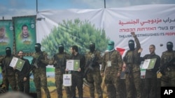 2月22日在加沙地带中部努塞拉特,以色列人质在巴勒斯坦哈马斯武装份子的戒护下向台下挥手。